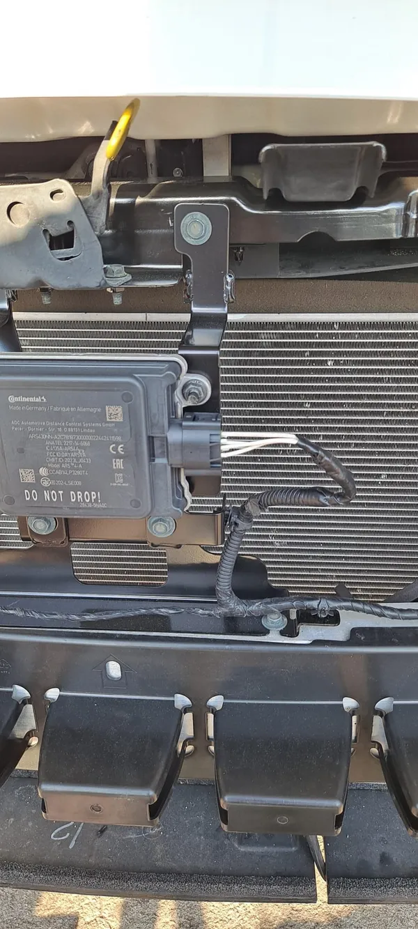 The replacement connector fitted to the module behind the front bumper, with the harness back in its loom and clipped down