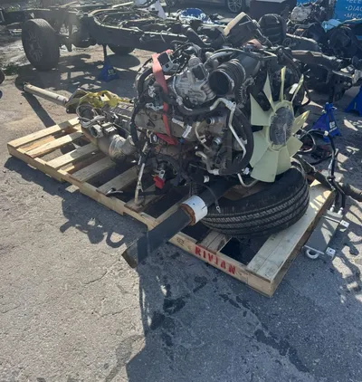 The engine, transmission, radiator and driveshaft out of the truck and resting on a wooden pallet on the ground