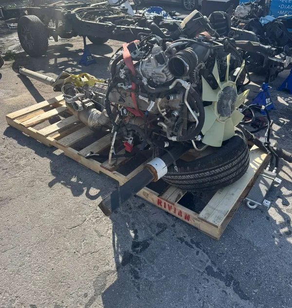 The engine, transmission, radiator and driveshaft out of the truck and resting on a wooden pallet on the ground