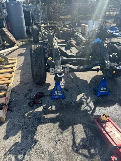 The bare pickup frame on jack stands with the suspension and steering still attached and the body lifted away