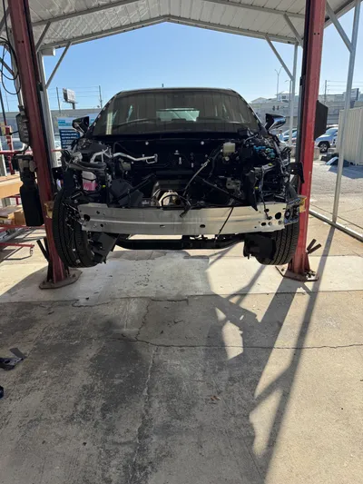 Head-on view of the same Lexus with the entire front end stripped and the engine bay empty, ready for structural repair