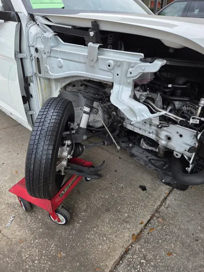 The rebuilt corner back together with the wheel refitted, the car resting on a red wheel dolly with the front end still open