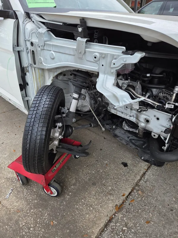 The rebuilt corner back together with the wheel refitted, the car resting on a red wheel dolly with the front end still open