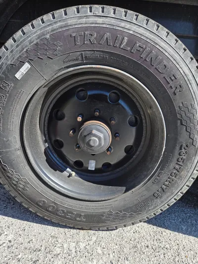 The trailer wheel and tyre refitted to the black steel rim with the lug nuts and grease cap back in place