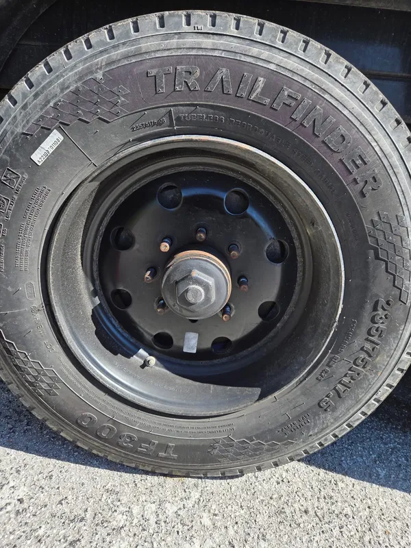 The trailer wheel and tyre refitted to the black steel rim with the lug nuts and grease cap back in place