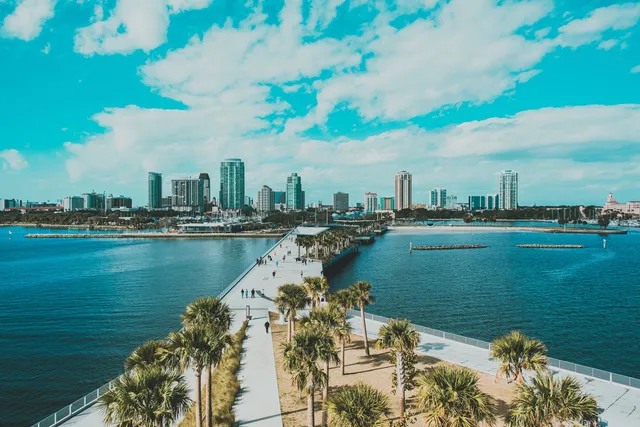 The downtown St. Petersburg skyline seen from above the St. Pete Pier, with palm-lined walkways leading back toward the waterfront