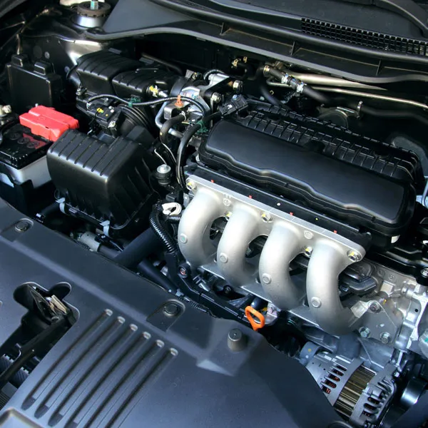 Close view of an engine bay with the intake and accessory drive exposed during a repair, taken outdoors beside the vehicle rather than in a workshop